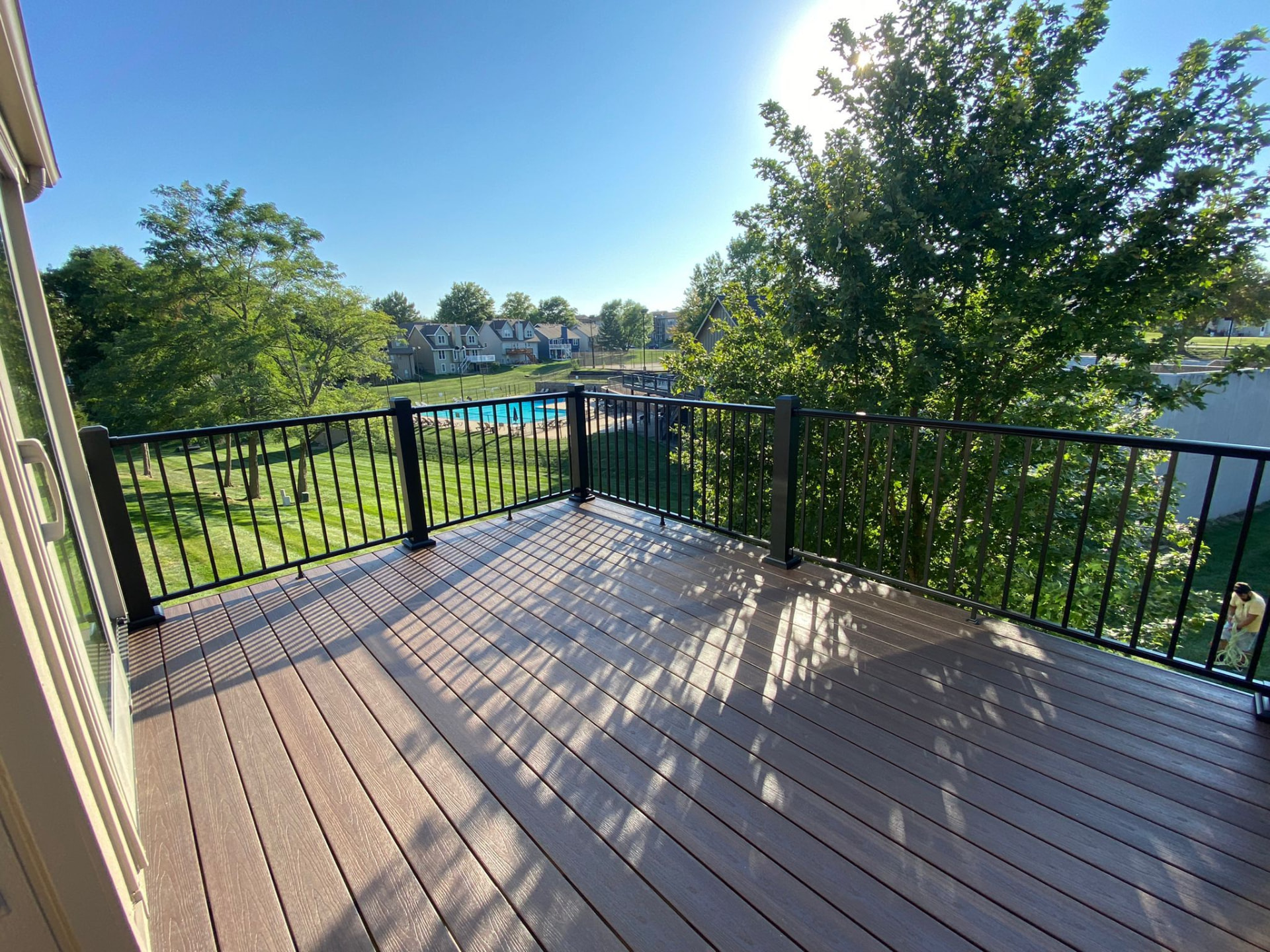 Composite deck with black aluminum railing overlooking a park and pool