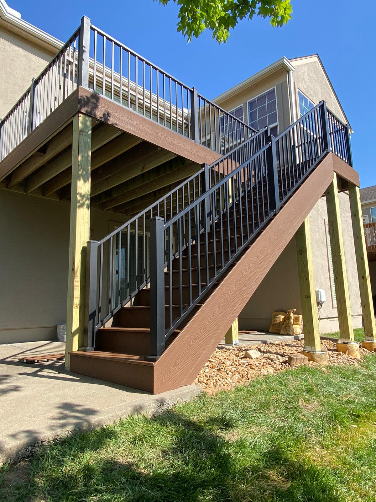 Second-story deck with brown composite stairs and black aluminum railing