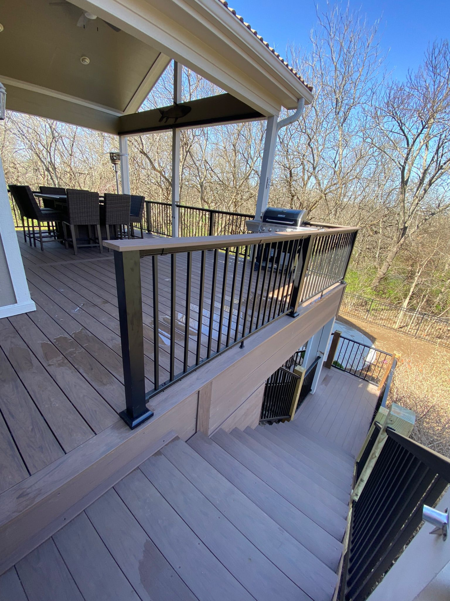 Covered outdoor kitchen deck with bar seating, grill and composite stairs