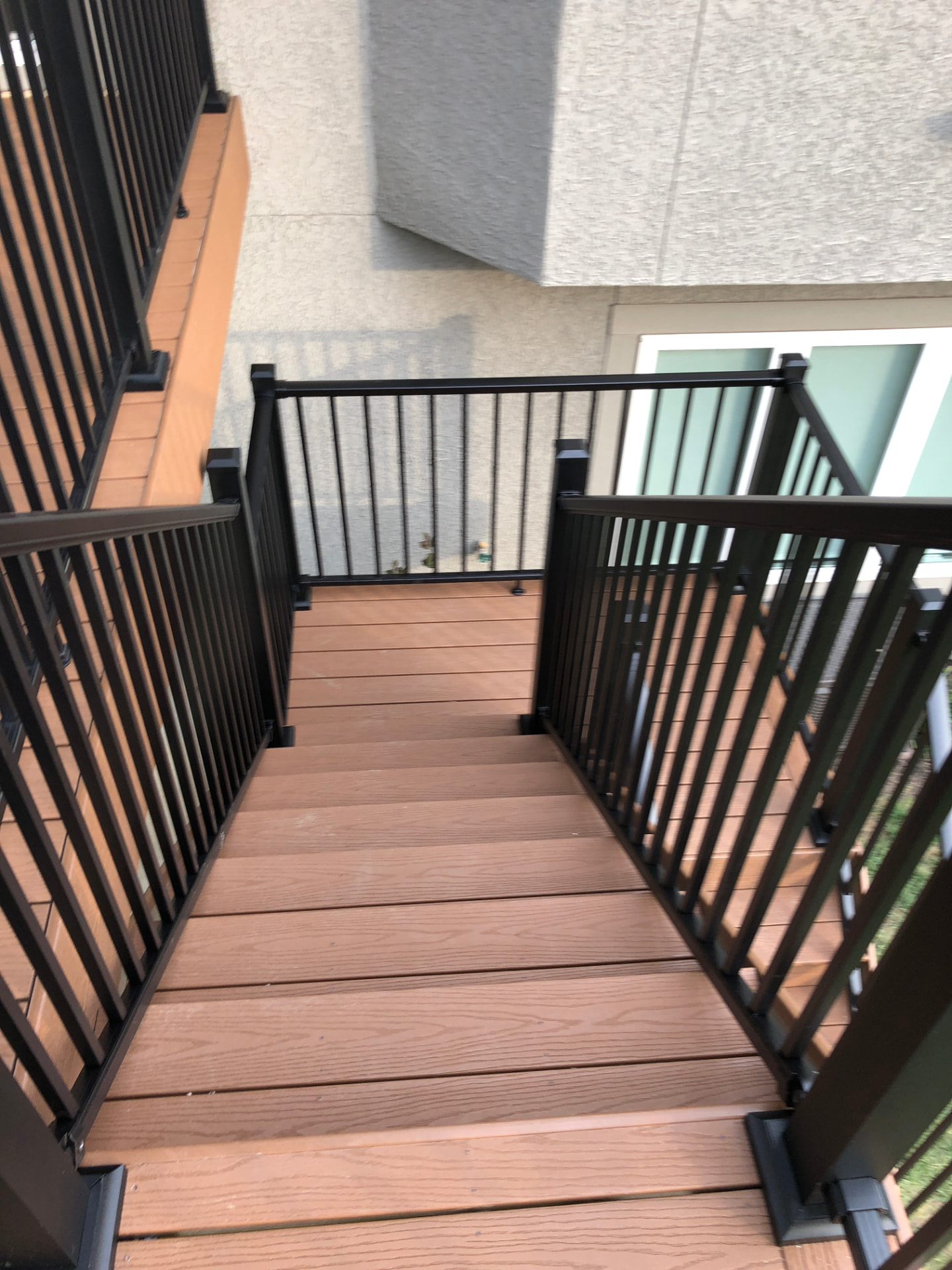 Deck stair landing with warm composite decking and black railing