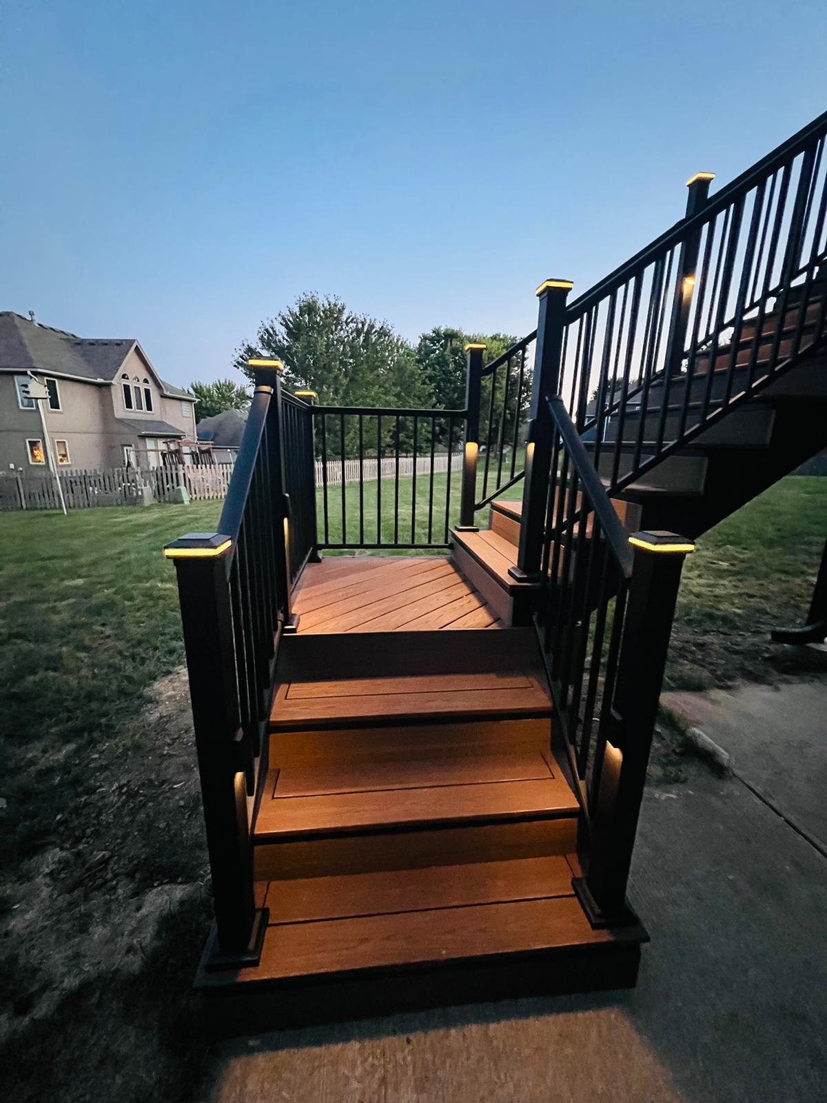 Deck stairs at dusk with lit post caps and warm-toned composite treads
