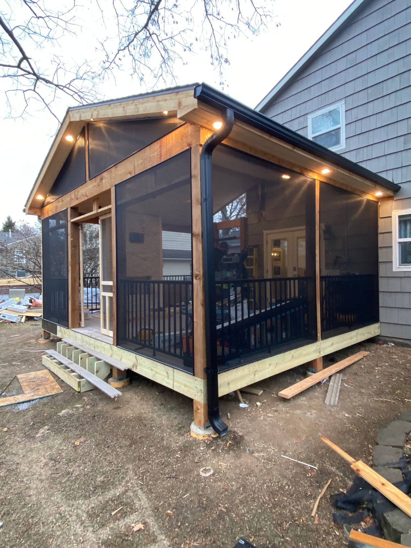 Exterior of a new screened porch addition with cedar framing and lighting