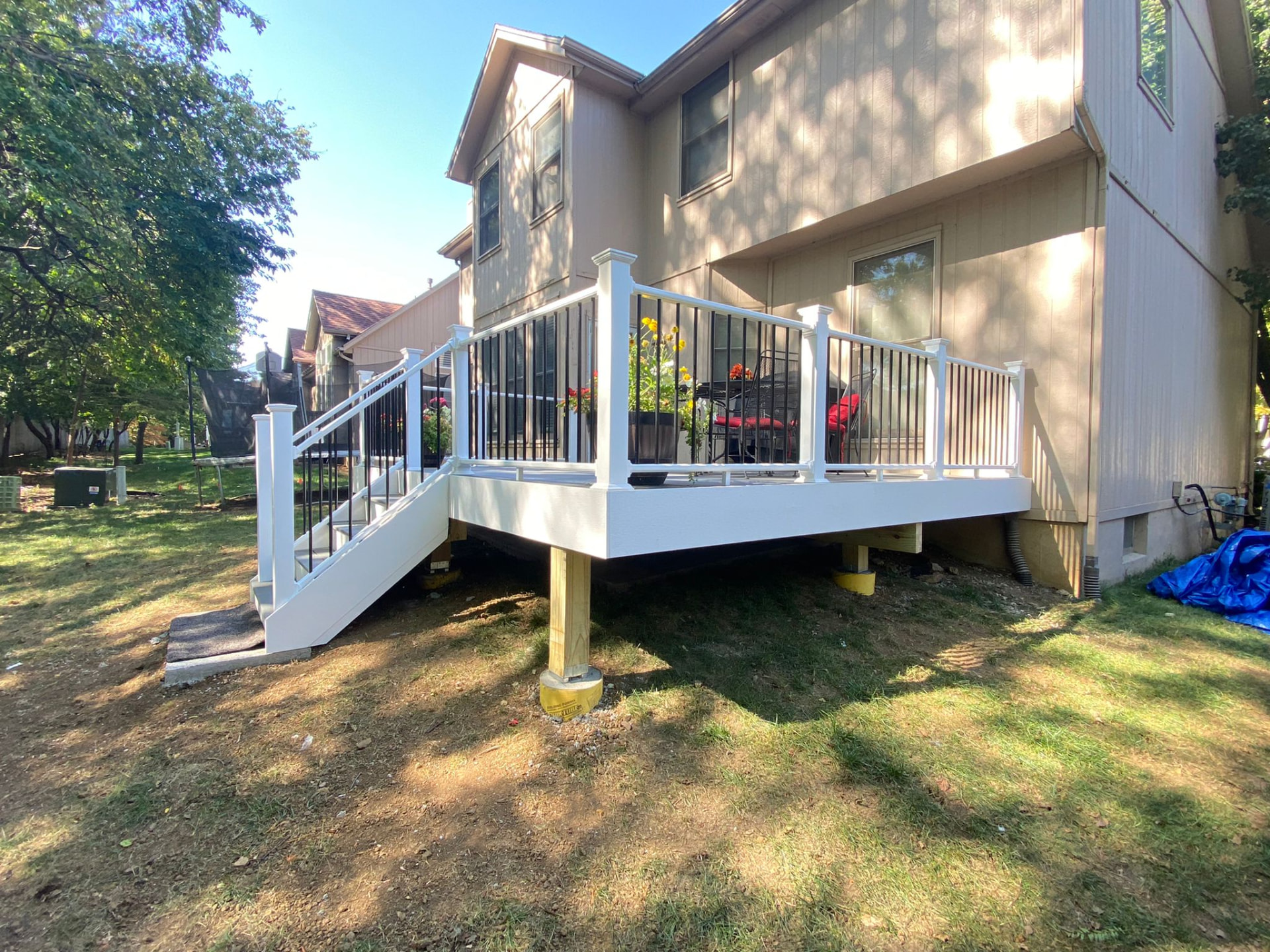 White railed deck with stairs attached to a two-story home