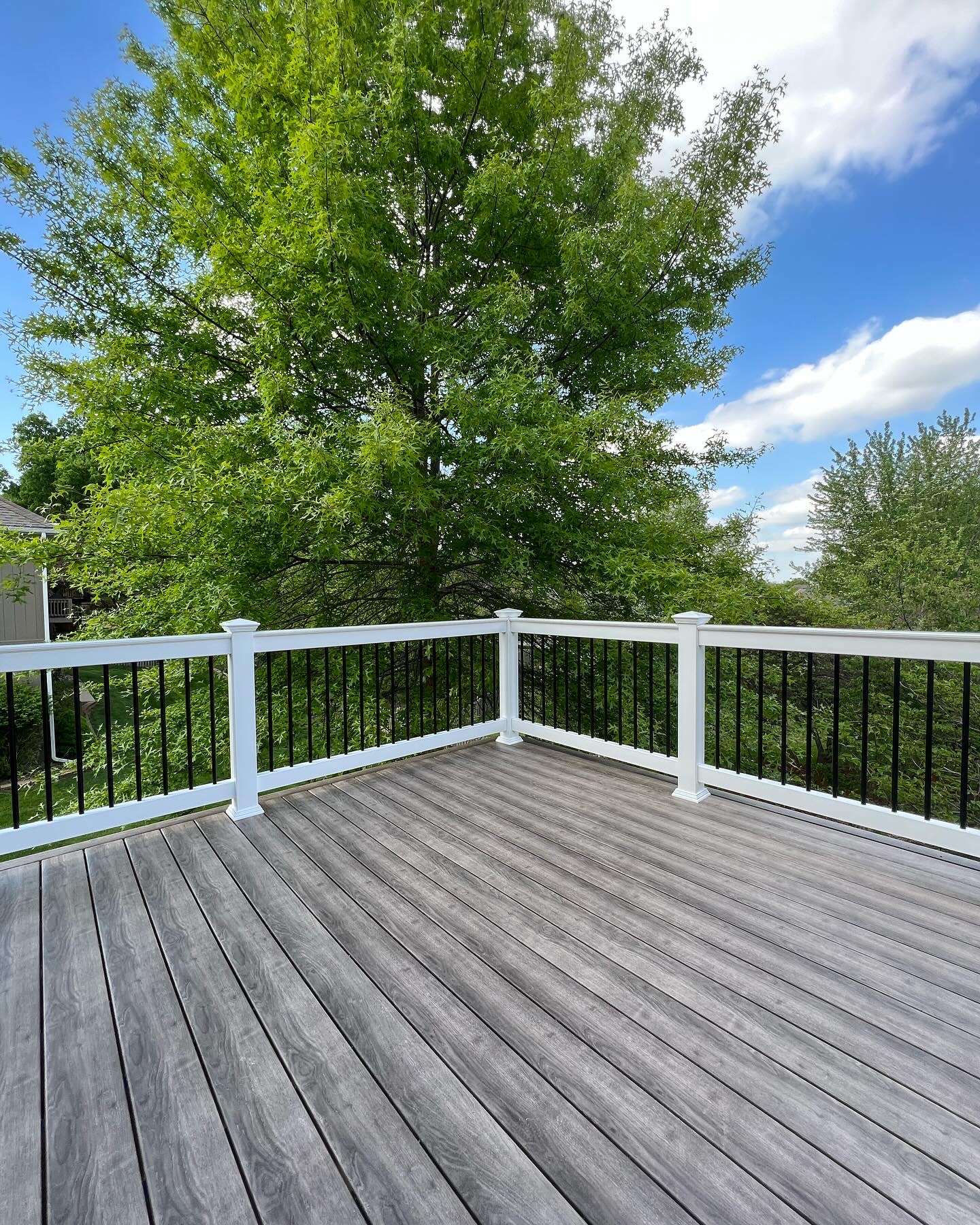 Gray composite deck with white vinyl railing and black balusters
