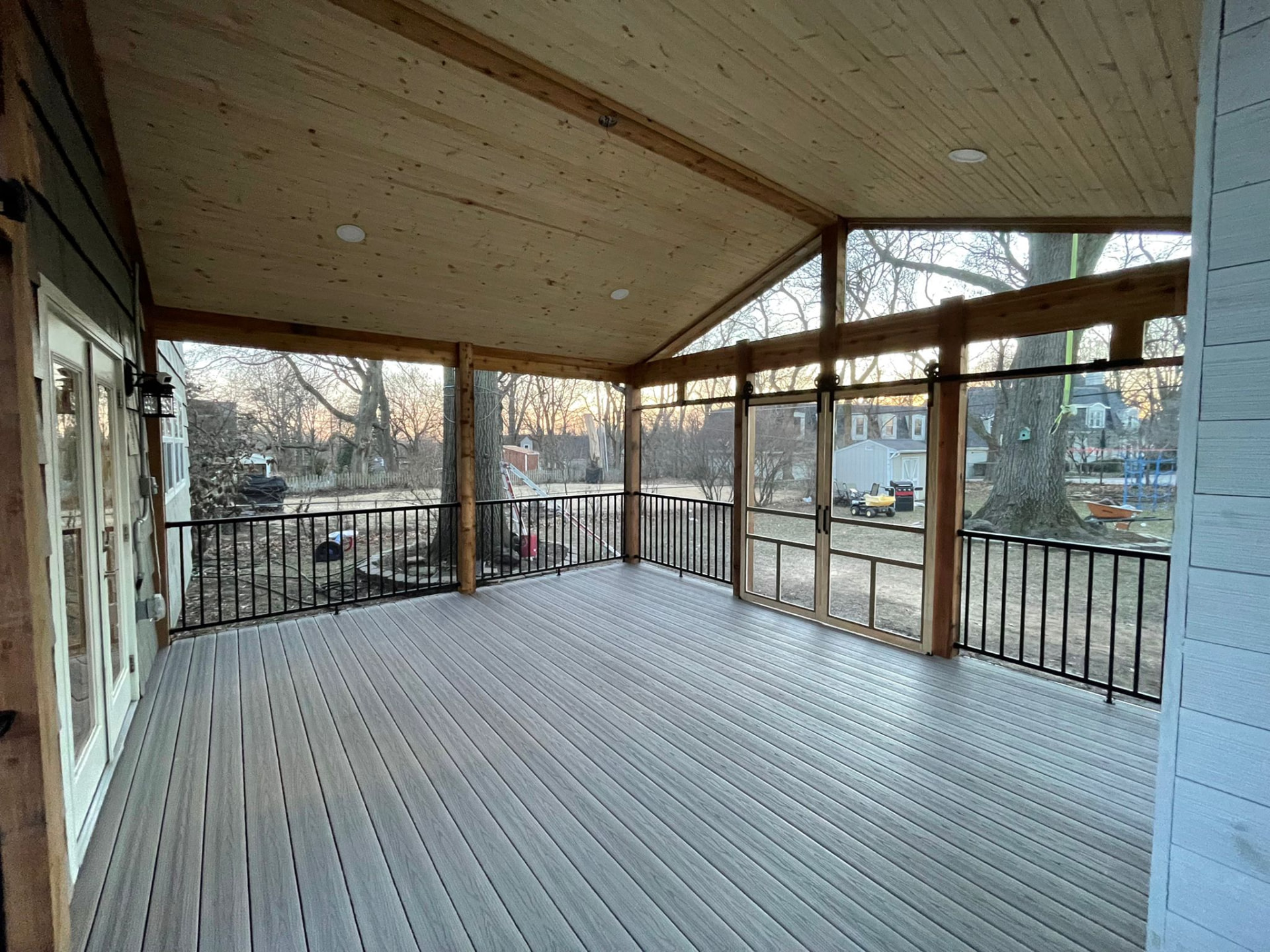 Screened porch with vaulted pine ceiling and gray composite flooring